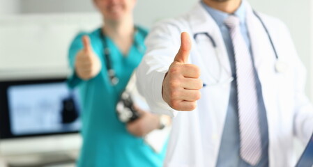 Two doctors show thumb up gesture with hands as public opinion improvement action closeup