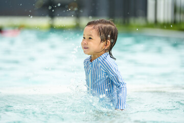 happy toddler baby playing water splashing in swimming pool
