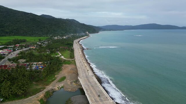 Flyover drone shot of coastal highway alongside scenic ocean shoreline at island of Catanduanes, Philippines.