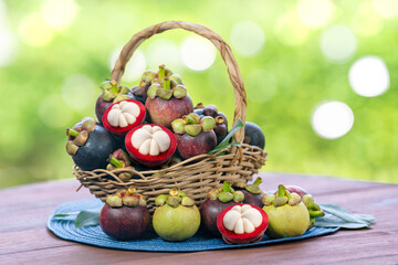 Red Mangosteen fruit on blurred greenery background, Red Mangosteen in Bamboo basket on wooden...