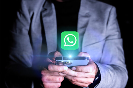 A man is holding a phone with a green WhatsApp logo on it