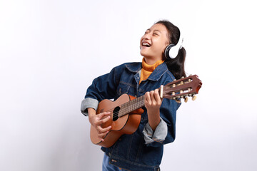 Obraz premium Happy casual style little girl playing guitalele or small guitar and singing isolated on white background