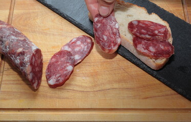 salchichon casero  mano cogiendo tapa cortada  grasa saturada 