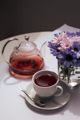 cup of tea with a teapot and flowers on the white table. Morning rituals
