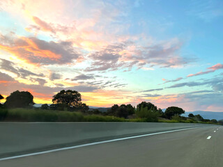 Beautiful pink and orange sky with white clouds above a road