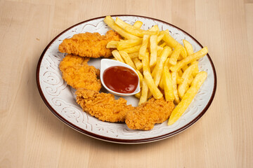 Plate of crispy fried chicken wings with French fries and a side of ketchup on a wooden table