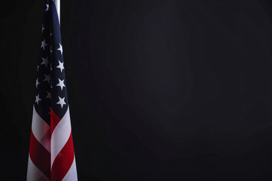 Photo of American flag on a black background with copy space, in a closeup view. USA national symbol for United States holidays or celebrations. Banner design template. Isolated on a studio backdrop.