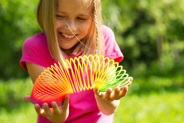 Happy girl with a rainbow magic spiral children's toy. 90s toy, nostalgia, retro.