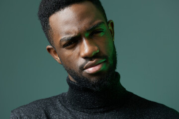 Stylish african american man in black turtleneck sweater posing confidently against a minimalist background