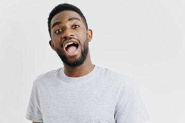 Surprised man in gray tshirt expressing shock and amazement on neutral white background