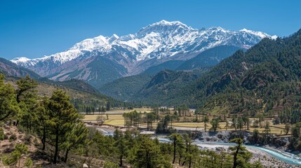 Snow-capped mountain range overlooking a green valley with a river.