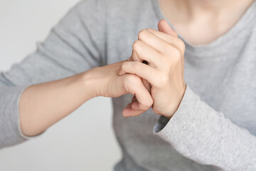 Close-up of a person cracking their knuckles. The image shows hands in action, wearing a grey...
