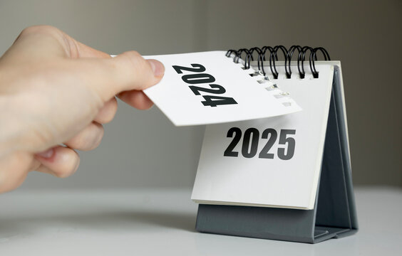a woman's hand turns over a calendar sheet. year change from 2024 to 2025.