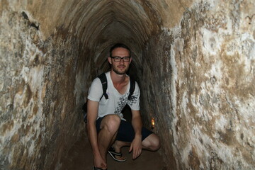 Young male tourist in tight Cu Chi tunnel near Ho Chi Minh City, Vietnam