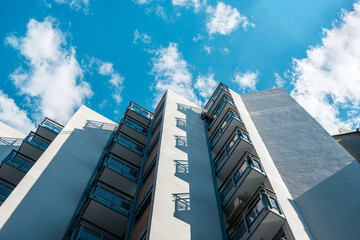 Low-angle view of a modern building with balconies, set against a vibrant blue sky. Contemporary architecture concept