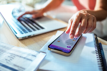 Close up of a middle aged woman holding smartphone with bank app