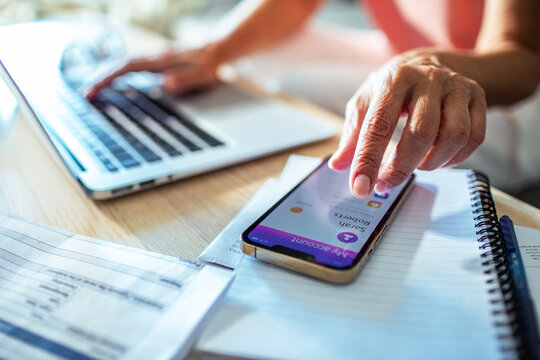 Close up of a middle aged woman holding smartphone with bank app