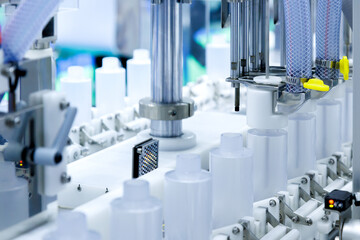 robot arm moving plastic bottle to conveyor belt of auto capping and labeling machine at cosmetic and skin care manufacturing. cosmetic industry and ai technology machinery concept.