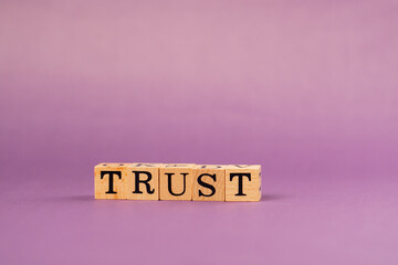 violet warm background with shadows woman hand put wooden cubes with black letters laid out word