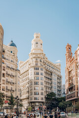 conic building with a central tower and surrounding urban street life in Valencia. The scene captures the city vibrant atmosphere and architectural diversity.