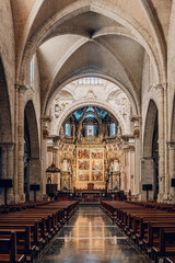 Magnificent interior of Valencia Cathedral with grand arches, detailed altar, and stained glass windows. The intricate design showcases the rich history and spiritual atmosphere.