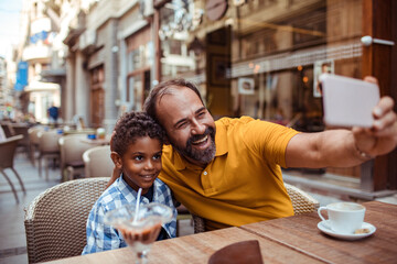 Father and son taking a selfie at an outdoor cafe with ice cream