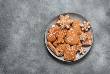 Assorted Christmas gingerbread cookies in a plate on a gray concrete background. Top view, flat lay, copy space.