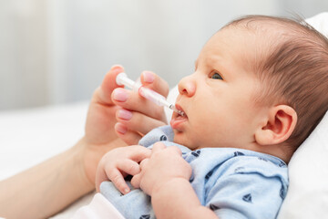 Newborn baby receiving liquid vitamin K from a dropper