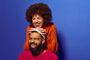 Young African American man and woman in vibrant attire laughing together, showcasing friendship and camaraderie.