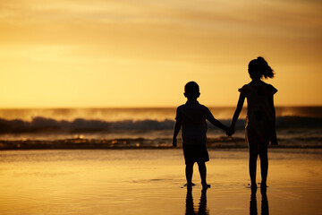 Beach, silhouette and children holding hands at sunset on holiday, vacation or travel together outdoor. Kids, back view and family siblings by sea waves for love or support on adventure in summer