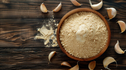 Fototapeta premium Top view flat lay of garlic powder in a wooden bowl and a bulb of garlic isolated on a wooden table background.