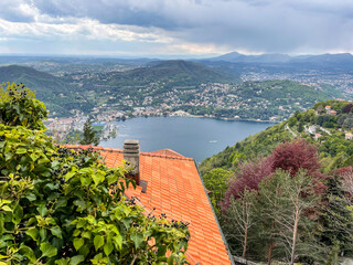 View of Lake Como and city from panoramic viewpoint near residential building in Brunate on cloudy spring day