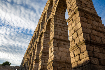 View from below of a detail of the impressive aqueduct of Segovia, Spain, with large stone blocks illuminated at dusk © AntonioLopez