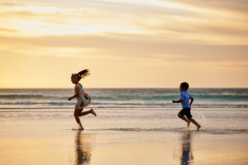 Fototapeta premium Beach, children and siblings running at sunset for playing games and enjoying exercise on ocean trip. Travel, kids and brother on sand at sea chasing sister in nature for holiday vacation or weekend
