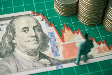 Businessman looking at US dollar banknote tear off as falling down graph tensely. Economy...