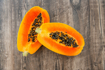Papaya fruit on a dark wooden background. Slices of sweet papaya, Halved papayas