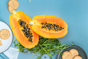 Papaya fruit and rucola on a blue background. Slices of sweet papaya and rucola on blue