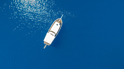 Aerial photo taken with a drone of a boat sailing in the blue clear waters of the Aegean Sea.