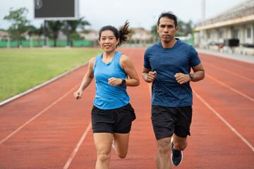 Obraz premium Asia mature woman and man runner training on racetrack and field