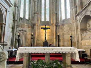 Stone altar and presbytery and stained glass windows in medieval Gothic style with candles and wooden cross in the Fortified Church of Leça do Balio.