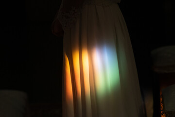Bride standing in church with rainbow light shining on her dress