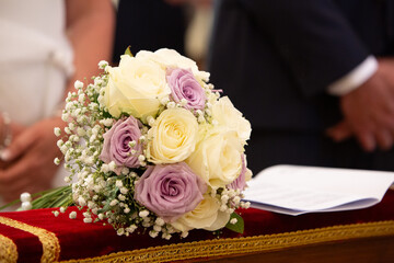 Beautiful wedding bouquet lying on red velvet cushion