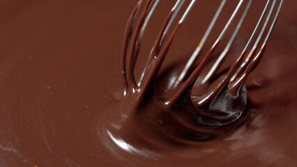 Smooth chocolate sauce being whisked.