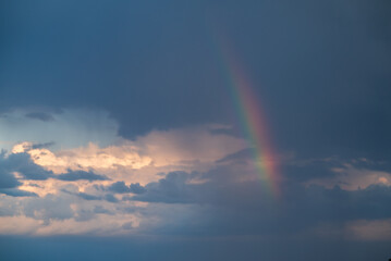 Dark blue clouds and light rainbow on the sky. Scenic view on the sky after the rain concept