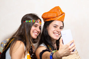 Two happy women wearing traditional clothes taking a selfie with smartphone