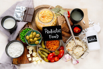 Probiotic food concept. Cabbage in jar, pickle, carrot on light wooden background