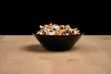Bowl of loaded fries topped with creamy sauce and grilled chicken on a wooden table