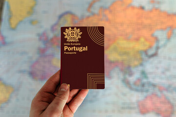 Man holding Portugal passport in hand and world map in background