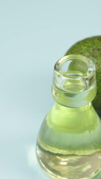 avocats et petite bouteille en verre d'huile, en gros plan, sur un fond bleu
