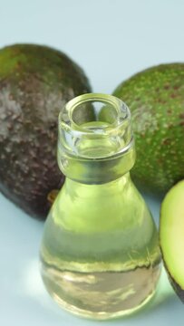 avocats et petite bouteille en verre d'huile, en gros plan, sur un fond bleu